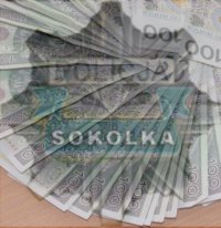 Odznaka policji z napisem &quot;Sokółka&quot;. W tle banknoty o nominale sto złotych.